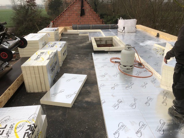 Werfbeeld van een plat dak in opbouw met isolatieplaten onder de EPDM-bedekking, illustratief voor dakisolatie langs de buitenkant