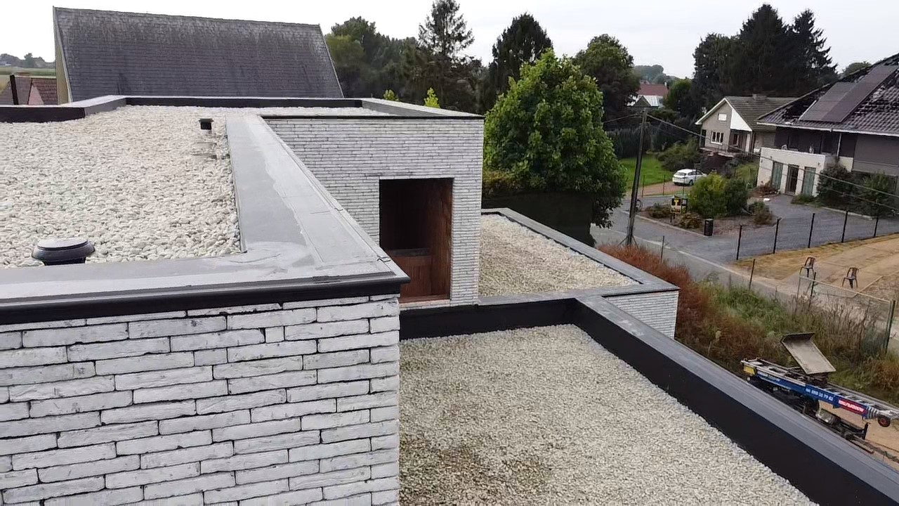 Werf- of dronebeeld van een plat EPDM-dak op een moderne woning met kiezelafwerking