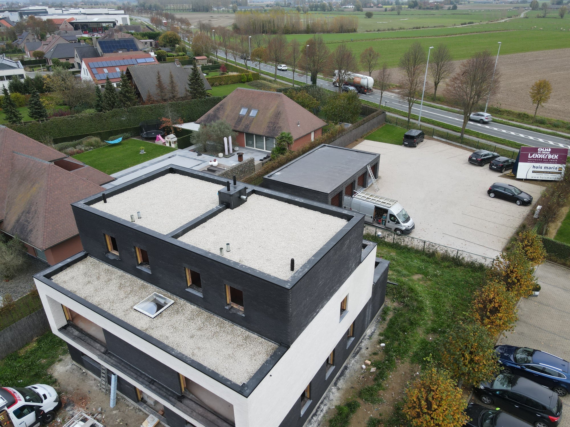 Luchtfoto van een woning met afgewerkt plat EPDM-dak met kiezelbedekking en strakke dakranden